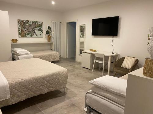 ein Hotelzimmer mit 2 Betten, einem Tisch und einem TV in der Unterkunft A casa di Lella in Budrio
