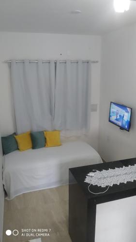 a white bed with yellow pillows and a table in a room at CASA DA NATY in Morro de São Paulo