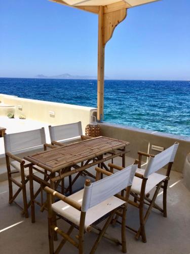 a wooden table and chairs on a balcony with the ocean at Poseidon House in Mandrakion