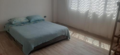 - une chambre avec un lit doté de draps bleus et une fenêtre dans l'établissement Villa lety, à Tibasosa