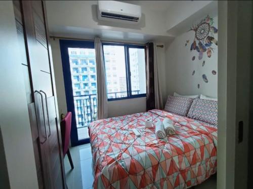1 dormitorio con 1 cama con edredón rojo y 2 ventanas en Jericho's Place, en Manila
