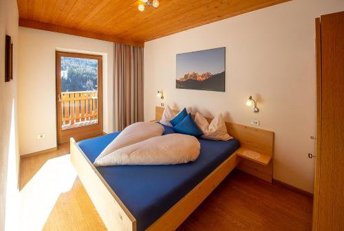 a bedroom with a bed with blue sheets and a window at Galreidhof in Funes