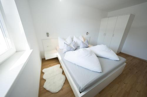 uma cama branca com almofadas num quarto em Austrian Apartments em Bad Goisern