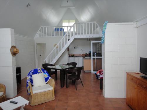 ein Wohnzimmer mit einem Tisch, Stühlen und einer Treppe in der Unterkunft Betela Beach House in Rarotonga
