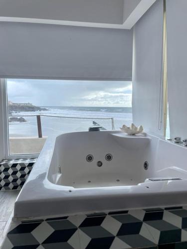a white bath tub with a view of the ocean at Castillos Del Mar in Rosarito
