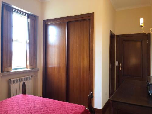 a bedroom with a pink bed and a wooden door at Casa das Eiras in Tondela