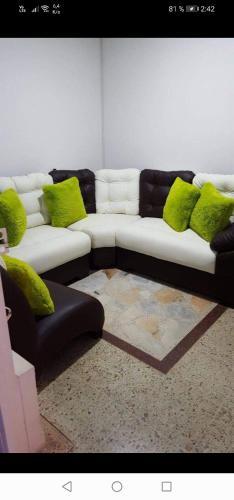a living room with a white couch with green pillows at Casa Villavicencio in Villavicencio