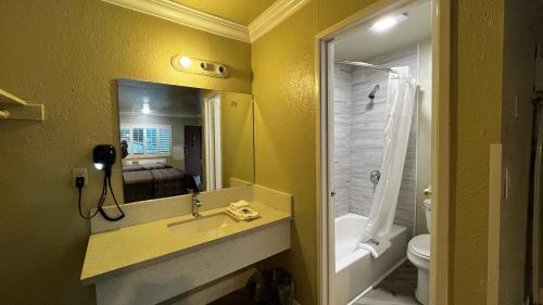 a bathroom with a sink and a toilet and a mirror at New American Inn & Suites in Anaheim