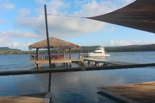 a dock with a boat in the water at Tongan Beach Resort in Utungake