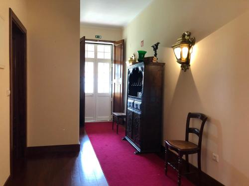 a hallway with a door and two chairs and a lamp at Casa das Eiras in Tondela