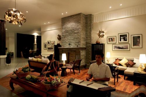 a man sitting in a living room with a keyboard at Le Palais Juliana in Luang Prabang