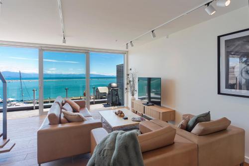 a living room with two brown couches and a television at Penthouse 37 - Nelson Waterfront Apartment in Nelson