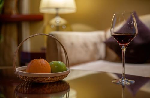 a glass of wine and a basket of fruit on a table at Chengdu Tianfu Sunshine Hotel in Chengdu