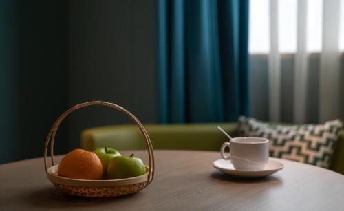 a basket of fruit and a cup of coffee on a table at Chengdu Tianfu Sunshine Hotel in Chengdu