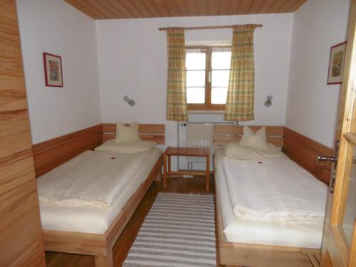 a room with two beds and a table and a window at Taffenreutherhof in Achenmühle