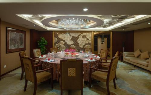a dining room with a table and chairs and a chandelier at Chengdu Tianfu Sunshine Hotel in Chengdu