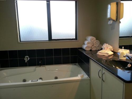 a bathroom with a bath tub and a sink at ASURE Albert Park Motor Lodge in Te Awamutu