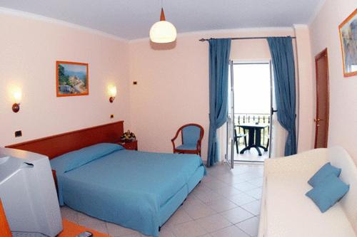 a bedroom with a blue bed and a balcony at Hotel Residence Tramonto in Rodi Garganico