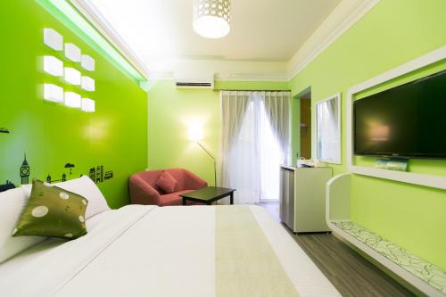 a green bedroom with a bed and a flat screen tv at 歐拉民宿 l 大空間包棟 l 親子溜滑梯 l 專業音響 in Taitung City