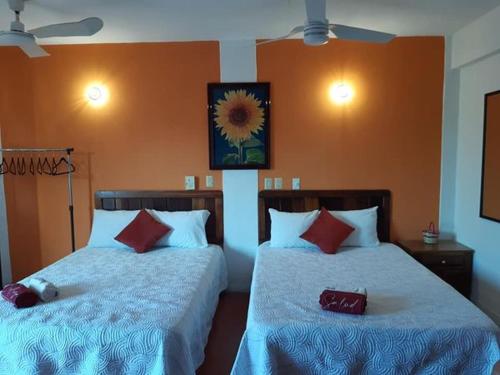 Hotel Doña Mary Huatulco في سانتا كروز هواتولكو: غرفة نوم بسريرين مع وسائد بيضاء وحمراء