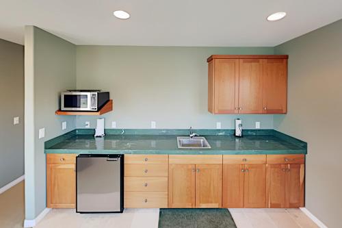 a kitchen with wooden cabinets and a black refrigerator at Big Retreat in Neskowin