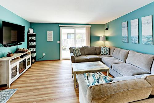 a living room with a couch and a tv at Azure Waves in Seaside