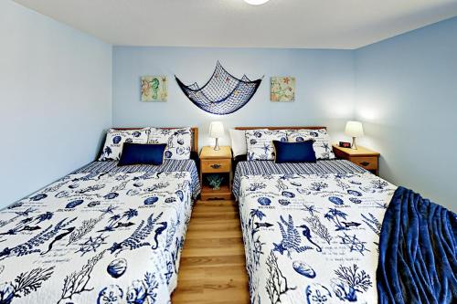 two beds in a bedroom with blue and white sheets at Azure Waves in Seaside
