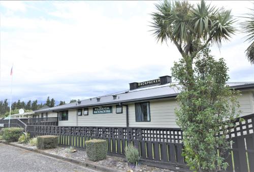 a house with a fence and a palm tree at Wilderness Backpackers in Haast