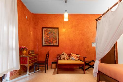 a bedroom with orange walls and a table and a chair at juSTa Morjim Beach Resort Goa - 80 Steps from Morjim Beach in Morjim