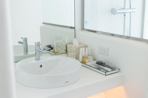 a white sink in a bathroom with a mirror at Yuki Suite Kourijima in Nakijin