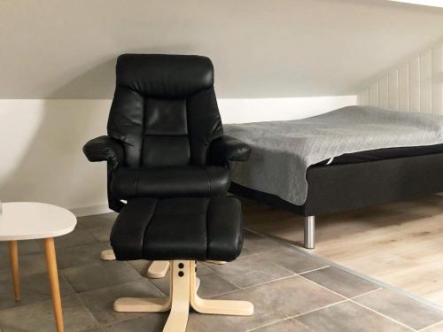 uma cadeira preta sentada ao lado de uma cama em One-Bedroom Holiday home in Hejls em Hejls