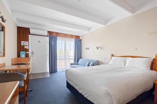 a hotel room with a bed and a desk and a table at Banjo Paterson Motor Inn in Lakes Entrance