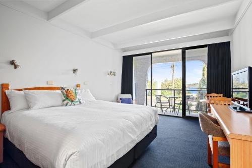 a hotel room with a bed and a desk and a desk at Banjo Paterson Motor Inn in Lakes Entrance