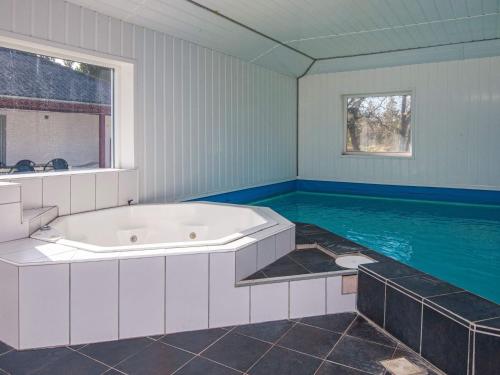 a large bathroom with a tub and a swimming pool at 18 person holiday home in R m in Kongsmark
