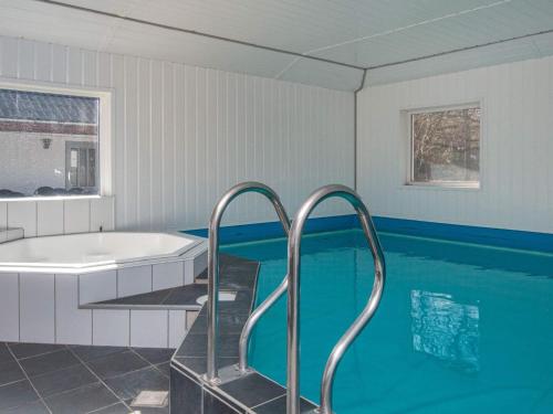 a bathroom with a tub and a swimming pool at 18 person holiday home in R m in Kongsmark