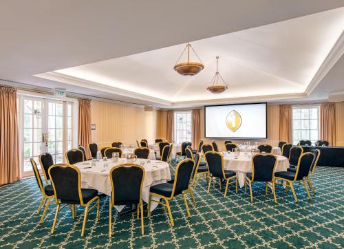 a conference room with tables and chairs and a screen at InterContinental Sanctuary Cove Resort by IHG in Gold Coast