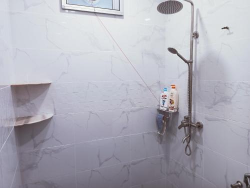een douche in een badkamer met witte tegels bij Chakkai Village Living Guest House in Kuala Perlis