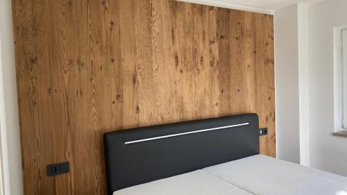 Un dormitorio con una pared de madera y una cama en Pia am See - Bio Design Appartement, en Bad Wiessee