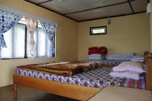 a bedroom with two beds and two windows at Vamoose Mahimalaya in Rinchingpong