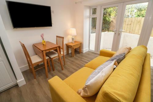a living room with a yellow couch and a table at Perran Pearl B in Perranporth