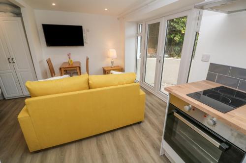 a yellow couch in a living room with a kitchen at Perran Pearl B in Perranporth