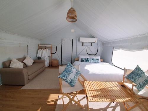 a bedroom with a bed and a couch in a tent at SOL Glamping at Khao yai in Ban Nong Makha