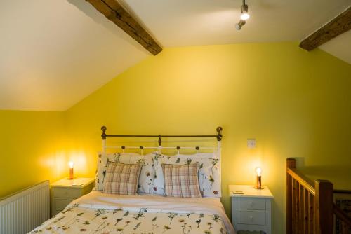 a bedroom with yellow walls and a bed with two lamps at The Sunshine Annex at Lower Fields Farm in Napton on the Hill