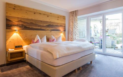a bedroom with a large bed with a wooden wall at Hotel Berlin Tegernsee in Rottach-Egern