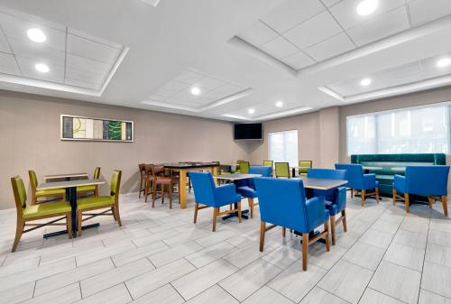 a dining room with tables and blue chairs at Holiday Inn Express Hotel & Suites Kansas City - Grandview by IHG in Grandview