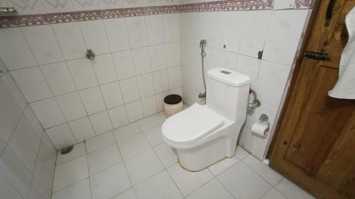 a white bathroom with a toilet in a room at THEHIMALAYANLIVING WHISTLING PINES in Mukteswar