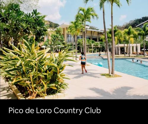 eine Person, die an einem Pool in einem Resort vorbeigeht in der Unterkunft Pico de Loro 2 BD Garden Loft with Lagoon View in Nasugbu