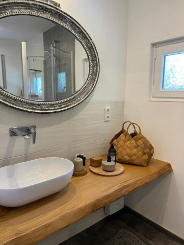 La salle de bains est pourvue d'un lavabo blanc et d'un miroir. dans l'établissement Ferienhaus Siesta Hahnenklee mit großem Grundstück, à Hahnenklee