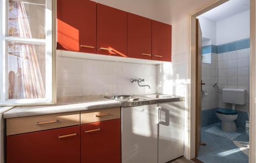 a kitchen with red and white cabinets and a toilet at Awesome Home In Koromacno With Kitchen in Koromačno