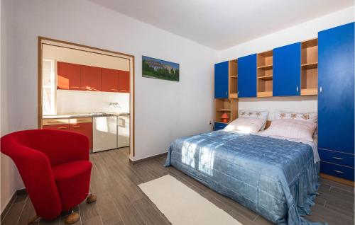 a bedroom with a bed and a red chair at Awesome Home In Koromacno With Kitchen in Koromačno